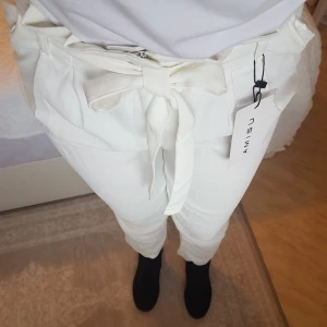 NYA, vita paperbag-byxor - Nya med lappar ~ Polyester, ca ankellånga (är 167cm). Stl 38 känns inte rättvis, snarare 36.. iaf för trång modell till min kroppstyp & får bättre passform på nån annan än på bild. ~ STOR rensning i min shop ~ Välj 5 för 100kr (gäller där det står) ~