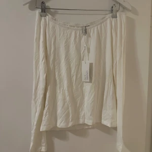 Vit off shoulder topp från NLY Trend - Säljer en superfin vit off shoulder top från NLY Trend. Den är enkel och stilren med en elastisk midja för extra komfort. Perfekt för både vardag och fest!