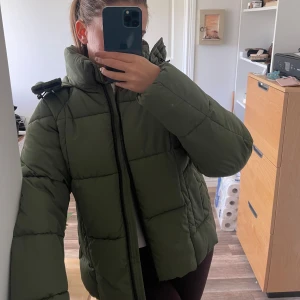 Grön pufferjacka  - Jättesnygg mörkgrön vinterjacka, den går att spänna till vid ryggen för och reglera hur stort den sitter. Den har knappast varit använd så är i nyskick! Tål en hel del regn och är super varm! Det är storlek S och jag är 164 cm lång