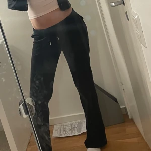 Svarta mjukisbyxor med snörning - Säljer ett par svarta mjukisbyxor som är superbekväma och perfekta för mys dagar. De är låg midjade och snörning i midjan för bästa passform. Byxorna har också snygga knappar som detaljer på baksidan. Perfekta för höst och vinter!💕