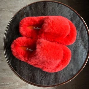 Julklappstips Röda fluffiga tofflor - Mysiga och varma röda tofflor med fluffigt pälsmaterial. Perfekta för att hålla fötterna varma under kalla dagar. De har en enkel slip-on design för bekvämlighet.