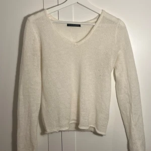 Vit stickad tröja från brandy Melville  - Mysig vit stickad tröja från Zara med v-ringning. Perfekt för kyligare dagar med sin mjuka och bekväma passform. Långärmad och enkel design som passar till det mesta.