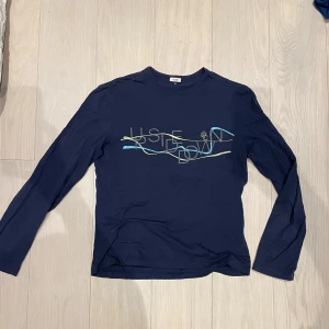 Longsleeve VJC - Säljer en mörkblå longsleeve från Ver sace jeans coutore. Plick tar bort alla ads där jag skriver Ver sace normalt vet ej varför. Tröjan har ett grafiskt tryck i ljusblått och beige på framsidan. Storlek XXL för en viss passform men sitter snyggt på mig som bär M och även mindre.