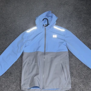 Blå och grå jacka från Under Armour - Säljer en snygg blå och grå jacka från Under Armour. Pga inte riktigt kommit till andvändning.     Säljer varan för 450 för att den är in princip oanvänd och kostar 799 nypris då den är i storlek junior. Den sitter bra på mig och jag är 181 långmen funkar nog ner till 172 då den sitter rätt tajt och kort i ärmarna 