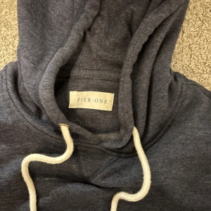 Mörkblå hoodie från Pier One - Säljer en stilren mörkblå hoodie från Pier One. Den har en klassisk design med justerbar huva och en stor ficka framtill. Perfekt för en avslappnad look.storlek S nästan helt oanvänd 