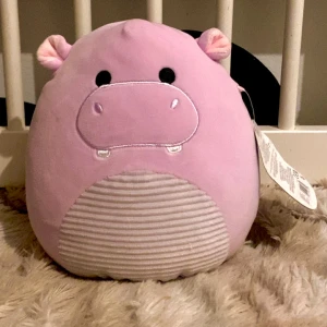 Rosa flodhäst Squishmallow - Mjuk och gosig rosa flodhäst Squishmallow vid namn Hanna. Perfekt för kramar och dekoration. Den har en söt design med små öron och en randig mage. Inga defekter va ja vet pris kan diskuteras ❤️