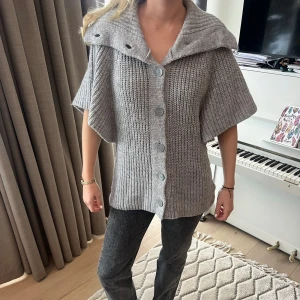 Grå stickad kofta med knappar - Säljer en mysig grå stickad kofta med stora knappar framtill. Koftan har korta ärmar och en bred krage som ger en avslappnad look. Perfekt för kyliga dagar❤️‍🔥❤️‍🔥