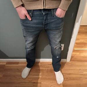 Blå jeans med slitningar - Säljer mina blåa jeans med slitningar från Jack n Jones. Nypris 900. Mitt pris 300 (priset är ej hugget i sten). Strlk 30/30, skriv vid funderingar. 