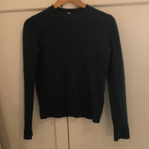 Mörkgrön kashmirtröja från Uniqlo - 100%KASHMIR Säljer en elegant mörkgrön kashmirtröja från Uniqlo. Tröjan har en klassisk design med rund hals och långa ärmar, perfekt för kyligare dagar. Den är mjuk och bekväm, vilket gör den till ett stilrent tillskott i garderoben. 
