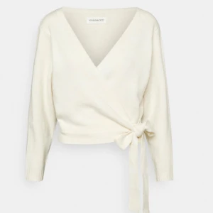 Vit omlottopp från Even&Odd Zalando  - Säljer en stilren beige omlottopp från Even&Odd med knytning i sidan. Toppen har en v-ringad design och långa ärmar, perfekt för en elegant look. Ursprung pris 339kr