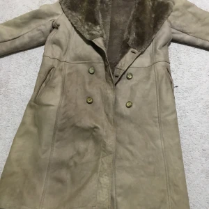 Beige mockakappa med pälsfoder - Säljer en stilren beige mockakappa med mjukt pälsfoder och dubbelknäppning. Perfekt för kyliga dagar med sin långa design och klassiska look.