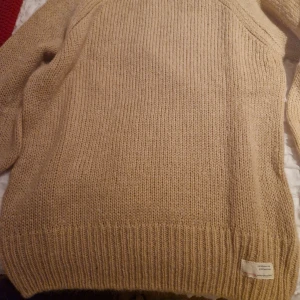 Beige stickad tröja från Odd Molly - Säljer en mysig beige stickad tröja från Odd Molly med ett vackert hålmönster på  baksidaTröjan har långa ärmar och ribbstickade muddar vid ärmslut och nederkant. Perfekt för kyliga dagar!