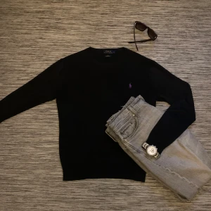 Svart tröja från Polo Ralph Lauren - Snygg svart tröja från Polo Ralph Lauren i slim fit. Tillverkad av mjuk pima bomull med ett lila broderat logotypmärke på bröstet. Perfekt för en stilren look. Riktigt skön tröja med härlig passform. Använder sällan så säljer nu! 