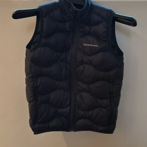 Blå dunväst från Peak Performance - Säljer en marinblå  dunväst från Peak Performance med dragkedja i mycket bra skick. Modell Helium. Nypris 1400kr.
