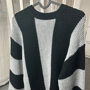 Svart och grå randig stickad tröja - Säljer en snygg stickad tröja i svart och grått med breda ränder. Tröjan har en rund hals och långa ärmar, perfekt för kyligare dagar. Den har en avslappnad passform som ger en skön och bekväm känsla.