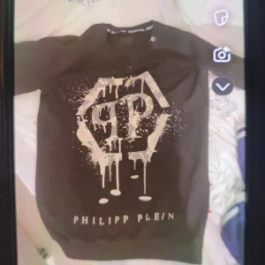 Svart tröja från Philipp Plein - Snygg svart tröja från Philipp Plein med ett stort, iögonfallande tryck i vitt framtill. Perfekt för en cool och avslappnad stil.