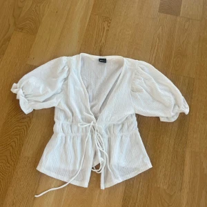 Vit blus från Gina Tricot - Säljer en superfin vit blus från gina med puffiga armar och en snygg knytning framtill❣️