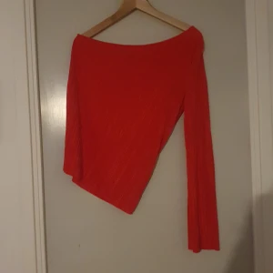 Röd offshoulder topp - Säljer en snygg röd offshoulder topp med lång ärm. Toppen har en ribbad struktur som ger en cool look. Perfekt för en utekväll eller fest!