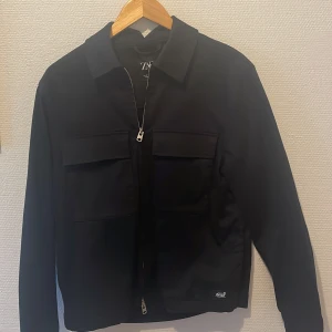 Svart jacka från Zara - Säljer en stilren svart overshirt från Zara. Den har en dragkedja framtill och två stora fickor på bröstet, 6 fickor i totalt. Overshirt är långärmad och har en klassisk krage. Perfekt för höst och vår, är i perfekt skick 10/10