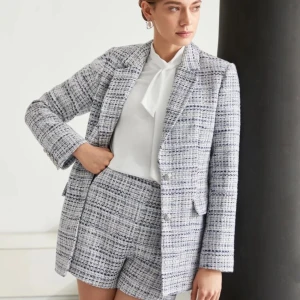 Rutig kavaj och shorts från Vero Moda - Snyggt set med rutig kavaj och matchande shorts från Motf. Kavajen har en klassisk passform med knappar framtill och shorts med hög midja. Perfekt för en stilren look.