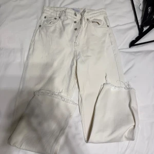 begie jeans med fransar - Snygga begie jeans med fransiga detaljer vid bensluten. De har en klassisk femficksdesign och knappar framtill. Perfekta för en stilren look.