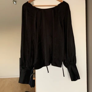 Svart blus från Banana Republic - Elegant svart blus från Banana Republic med långa ärmar och knytband vid ryggen. Endast andvänd 1-2 gånger. Pris går att diskutera vid snabb affär. Tveka inte med att höra av dig vid funderingar och frågor.
