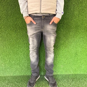 Grå jeansbyxor - Snygga grå jeans med en lätt tvättad look. De har en klassisk femficksdesign och knappgylf. Perfekta för en avslappnad stil.