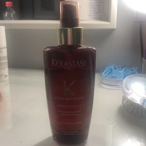 Kérastase Aura Botanica Essence D'Éclat - Kérastase Aura Botanica Essence D'Éclat är en återfuktande oljedimma i en elegant brun flaska med gyllene detaljer. Perfekt för att ge håret en naturlig glans och mjukhet. Flaskan rymmer 100 ml och har en praktisk sprayfunktion för enkel applicering.