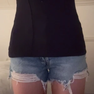 Blå jeansshorts från Zara - Säljer ett par jätte snygga blå jeansshorts från Zara med fransiga kanter och slitna detaljer. Dom är i mycket bra skick