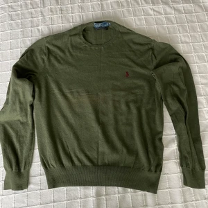  Polo Ralph Lauren tjocktröja - Säljer en stilren grön tröja från Polo Ralph Lauren i bomull. Tröjan har en broderad logotyp på bröstet och långa ärmar med ribbade muddar. Perfekt för en avslappnad och klassisk look. Otroligt bra kvalitet, tröjan är i materialet prima cotton som är Ralph Laurens mer exklusiva material. Tröjan har 10/10 ventilation och bara använd ett fåtal gånger. Skriv gärna om du har frågor eller funderingar 