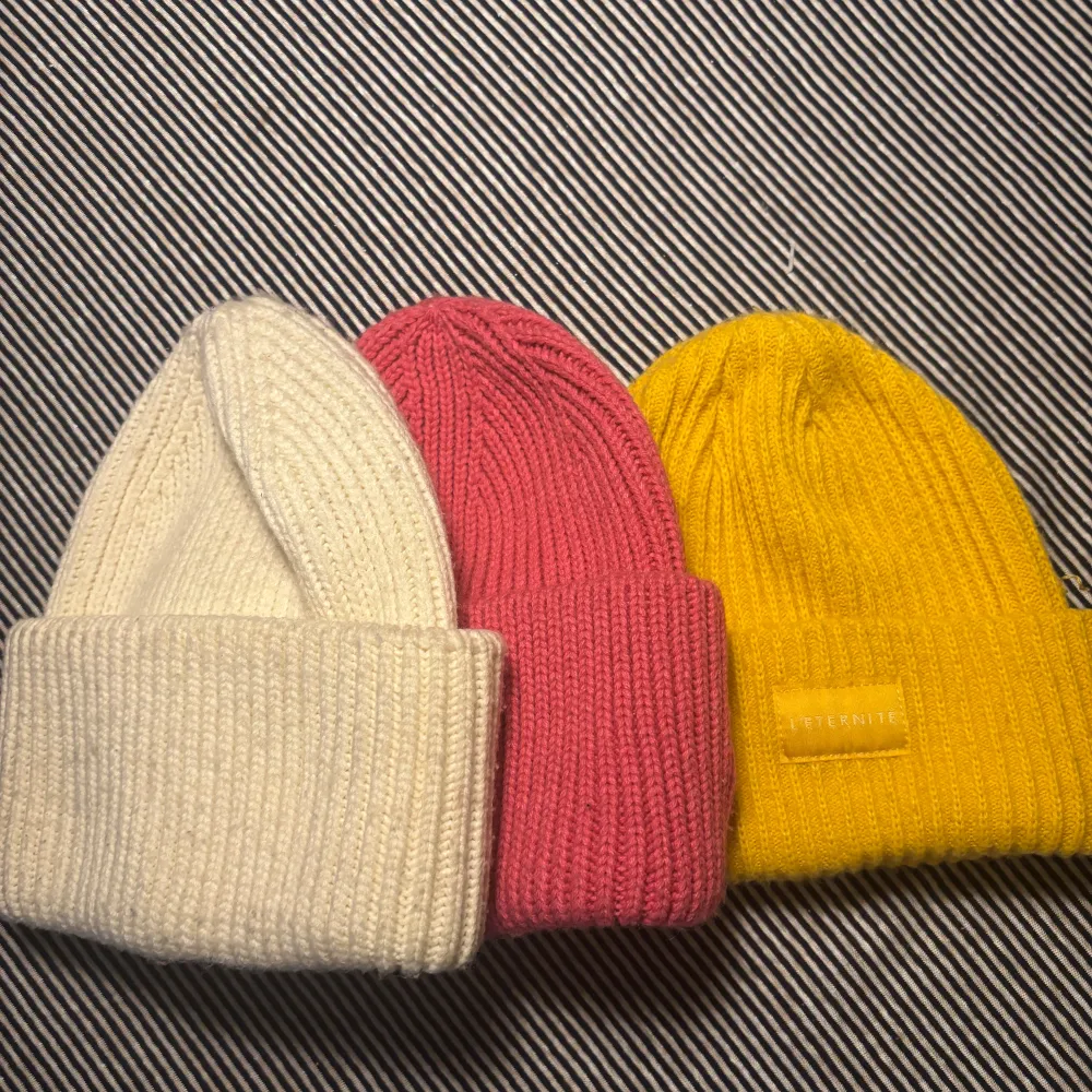 Säljer tre stickade mössor i färgerna vit, rosa och gul. Mössorna har en ribbad design och är perfekta för att hålla dig varm under kyliga dagar. De är mjuka och bekväma att bära.. Asusteet.