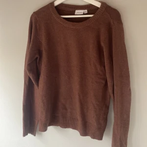 Brun stickad tröja från VILA - Säljer en mysig brun stickad tröja från VILA. Tröjan har långa ärmar och ribbstickade muddar vid ärmslut och nederkant. Perfekt för kyliga dagar!