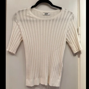 Vit topp från JDY - Säljer en stilren, knappt använd, vit topp från JDY. Toppen har korta ärmar och ett diskret mönster som ger en elegant touch. Perfekt för en avslappnad men ändå chic look.  Mått:  Byst: 38 cm  Midja: 38 cm Längd: 53 cm Innerärm: 13 cm