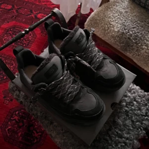 UGG lowmel  - Snygga svarta sneakers från UGG med robust sula och breda snören. Skorna har en stilren design  och är perfekta för en casual look. De är tillverkade i en kombination av syntet och mocka för extra komfort och hållbarhet. Använda 1 gång utomhus 