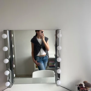 Grå pälsväst med virkad rygg - Säljer en snygg grå pälsväst med en unik virkad detalj på ryggen. Västen är perfekt för att ge din outfit en extra touch. Den är ärmlös och har en mjuk och fluffig känsla.