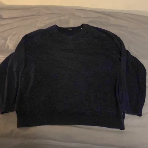 Mörkblå stickad tröja från Jack & Jones - Säljer en mörkblå stickad tröja från Jack & Jones i storlek XL. Men jag skulle säga att den passar L. Tröjan har en klassisk design med rund hals och är perfekt för kyligare dagar. Den är mjuk och bekväm, idealisk för både vardag och avslappnade tillfällen. 