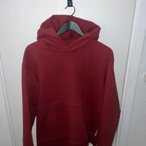 Röd hoodie från Acne Studios - Säljer en snygg röd hoodie från Acne Studios. Den har en klassisk design med en stor ficka framtill och en bekväm huva. Perfekt för en avslappnad stil. Passar både till jeans och joggers.