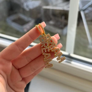 Guldiga örhängen med texten 'DREAM' - Snyggt halsband i guld med hängsmycke som stavar ordet 'DREAM'. Hängsmycket är täckt av glittrande stenar som ger en lyxig känsla. Perfekt för att lägga till lite bling till din outfit. Använda en gång