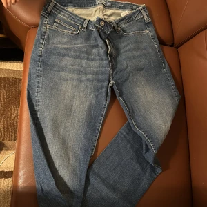 Blå jeans från Dressmann - Snygga blå jeans från Dressmann med en klassisk design. De har en normal passform och är tillverkade i slitstarkt denim. Perfekta för en avslappnad stil med fem fickor och knappgylf.