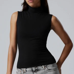 Svart trendig polotopp - Snygg svart ärmlös polotopp i stretchigt material. Perfekt för en stilren look, kan enkelt matchas med jeans eller kjol. Polokragen ger en elegant touch.