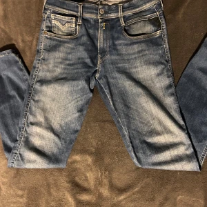 Blå jeans från Replay - Snygga blå jeans från Replay med klassisk femficksdesign och knappgylf. De har en diskret tvätt för en avslappnad look och är perfekta för vardagsbruk. Märkeslogga på bakfickan ger en extra touch. Storlek W29 L32