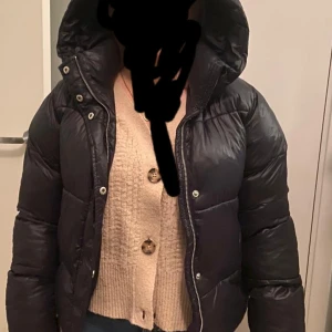 Nelly pufferjacka  - Säljer en svart glansig Nelly pufferjacka i stl 34. För liten för mig. Jag har stl 36. Fint skick. 