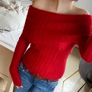 Röd offshoulder tröja från Body by Victoria - Säljer en snygg röd offshoulder tröja från Body by Victoria. Tröjan är ribbad och har långa ärmar, perfekt för en stilren look. Tillverkad i en mjuk blandning av kid mohair, nylon och akryl.