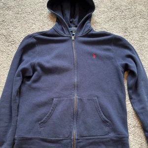 Mörkblå hoodie från Polo Ralph Lauren - Säljer en snygg mörkblå hoodie från Polo Ralph Lauren. Den har en röd broderad logga på bröstet. Sitter som en S. Mycket bra skick. Hör av dig vid funderingar. Pris går att förhandla