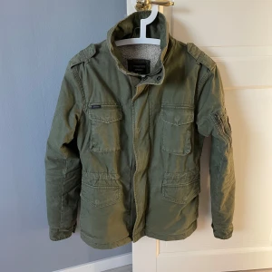 Superdry fieldjacket  - Tja säljer nu denna riktigt sköna fieldjacket från superdry! Fint skick! Perfekt till kallare tider. Nypris 1499kr. Strl xs men funkar nog även för en mindre S. Bara att fråga vid eventuella funderingar mvh 