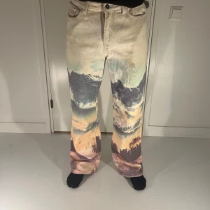 Mönstrade wide leg byxor från Jaded London - Unika wide leg byxor från Jaded London med ett fantastiskt landskapsmönster i dämpade färger. Byxorna har en hög midja och en avslappnad passform som ger en cool 90-talskänsla. Perfekta för dig som vill sticka ut med stil.