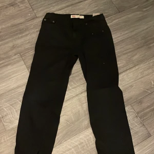 Svarta Levi's 502 Regular Taper jeans - Snygga svarta Levi's 502 Regular Taper jeans med en klassisk design. De har en avsmalnande passform och är perfekta för en stilren look. Jeansens svarta färg gör dem lätta att matcha med olika outfits.