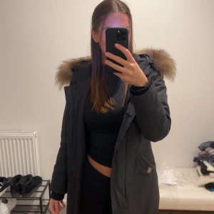 Jacka med päls - Snygg svart jacka med pälsdetaljer på huvan. Jackan har en klassisk design med knappar och en skön passform. Perfekt för kyligare dagar.