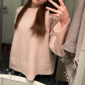 Ljusrosa stickad tröja - Mysig ljusrosa stickad tröja med långa ärmar och ribbade detaljer vid ärmslut och nederkant. Perfekt för kyliga dagar. Är i storlek 158/164 men sitter som en S.
