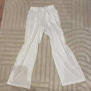 Vita linnebyxor med resårmidja - Snygga och bekväma vita linnebyxor med resårmidja och snörning. Byxorna har en loose passform och raka ben, vilket ger en avslappnad look. Perfekta för varma dagar med sina praktiska fickor både fram och bak. Som nya